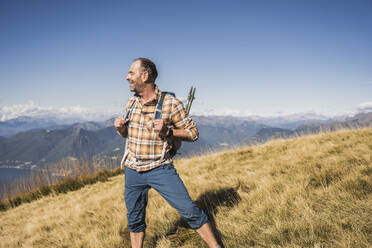 Lächelnder reifer Mann steht auf Gras an einem sonnigen Tag - UUF28894