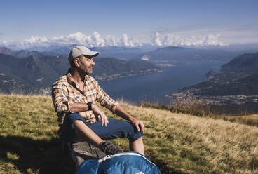 Wanderer, der sich auf einer Bank sitzend an einem sonnigen Tag ausruht - UUF28908