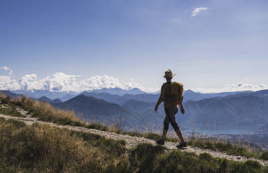 Hiker walking on footpath and looking at mountains - UUF28911