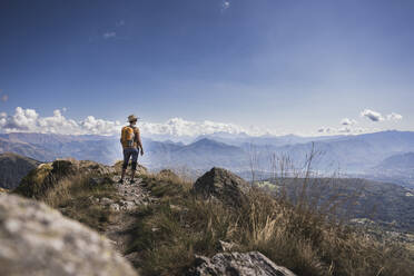 Wanderer, der auf einem Berg stehend die Wolken betrachtet - UUF28915