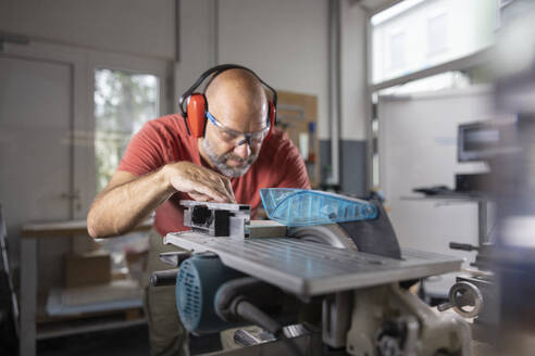 Focused carpenter cutting wood at workshop - CVF02433