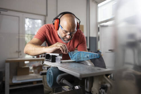 Carpenter wearing ear protectors working at workshop - CVF02436