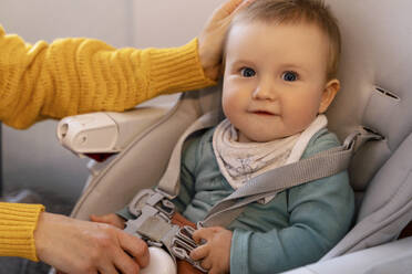 Cute smiling baby boy sitting on high chair with mother at home - NDEF00743