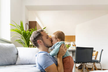 Vater küsst kleinen Jungen im Wohnzimmer zu Hause - NDEF00748