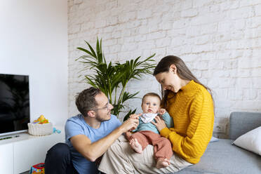 Happy parents spending leisure time with baby boy in living room - NDEF00754