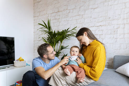 Glückliche Eltern verbringen ihre Freizeit mit einem kleinen Jungen im Wohnzimmer - NDEF00754