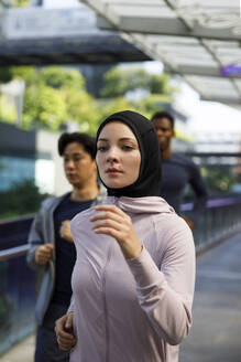 Frau mit Hidschab beim Joggen mit Freunden - IKF00897