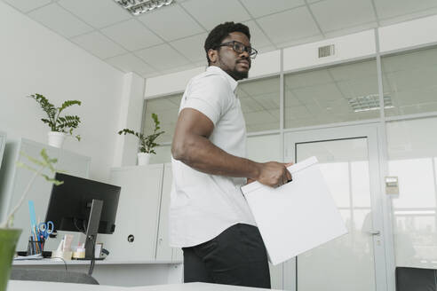 Junger Geschäftsmann trägt Box im Büro - OSF01743