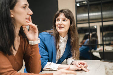 Businesswoman talking with office colleague at coffee shop - AMWF01413