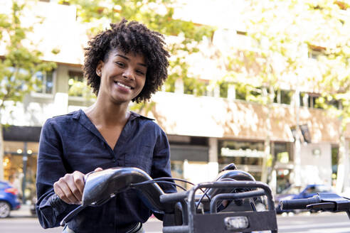 Smiling woman standing with electric bicycle - PNAF05345