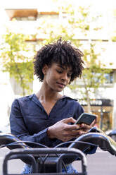 Young woman renting electric bicycle and using smart phone - PNAF05346