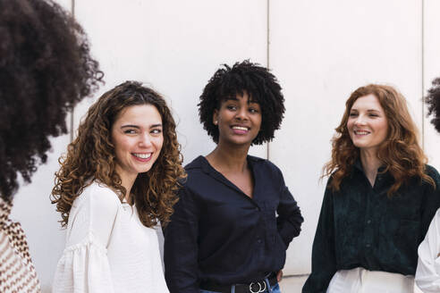 Lächelnde junge Geschäftsfrauen, die gemeinsam Zeit verbringen - PNAF05358