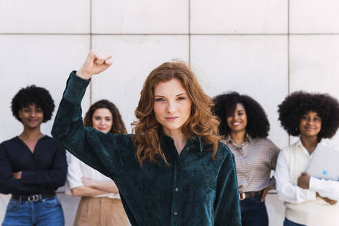 Confident businesswoman with colleagues standing in background - PNAF05366