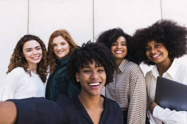 Fröhliche weibliche Führungskraft, die ein Gruppen-Selfie mit Kollegen macht - PNAF05367