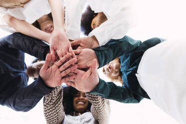 Happy businesswomen stacking hands and huddling together in unity - PNAF05369