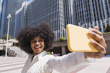 Happy businesswoman taking selfie through smart phone in office park - PNAF05438