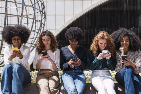 Geschäftsfrauen benutzen gemeinsam ein Smartphone im Büropark - PNAF05440