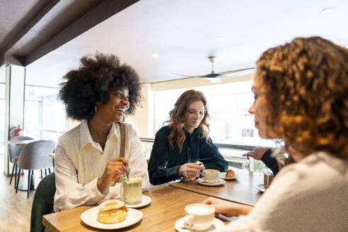 Glückliche Frau verbringt Zeit mit Freunden in einem Cafe - PNAF05443