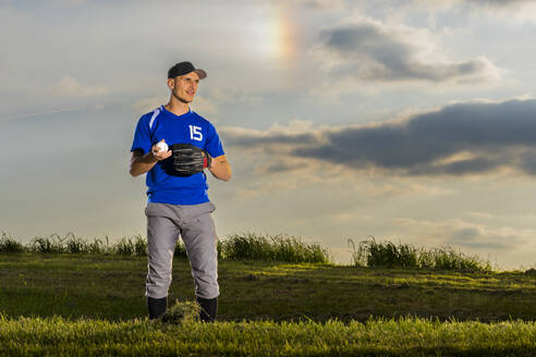 Mann spielt Baseball auf Gras in der Abenddämmerung - STSF03731