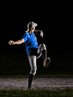 Junger Mann bereitet sich darauf vor, nachts einen Baseball zu werfen - STSF03747