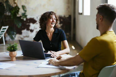 Happy young businesswoman having discussion with businessman in office - EBSF03578