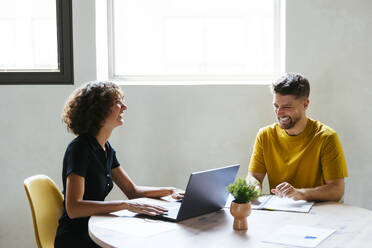 Happy businesswoman having discussion with businessman at desk - EBSF03579