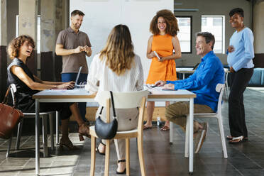 Happy business colleagues having discussion in meeting at office - EBSF03609