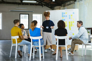 Happy businesswoman gesturing and discussing in front of whiteboard - EBSF03629