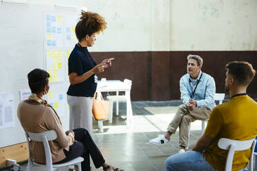 Businesswoman gesturing and explaining to colleagues in office - EBSF03631