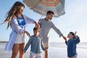 Happy family enjoying at beach on sunny day - ASGF03830