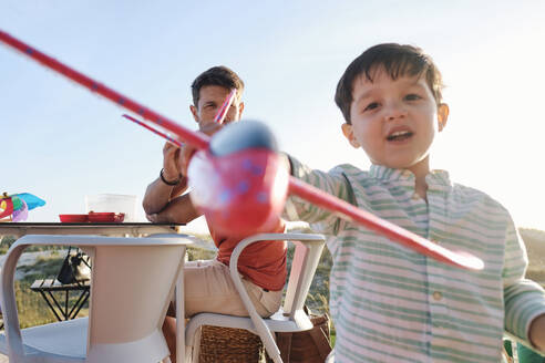 Junge spielt mit Spielzeugflugzeug an einem sonnigen Tag - ASGF03832