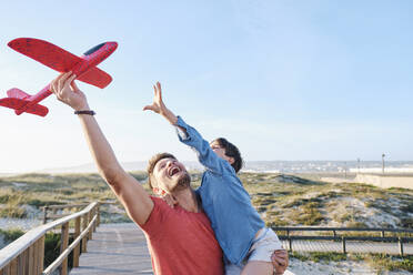 Glücklicher Vater und Sohn spielen mit Spielzeugflugzeug - ASGF03837