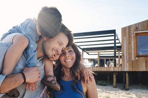 Happy family having fun in front of beach house - ASGF03844