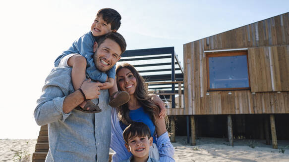 Happy father and mother with children enjoying at beach on sunny day - ASGF03847