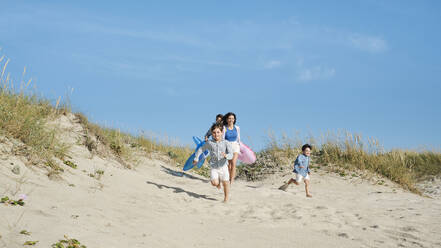 Glückliche Familie läuft am Strand unter Himmel - ASGF03848