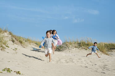 Glückliche Familie läuft am Strand an einem sonnigen Tag - ASGF03849