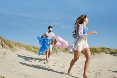 Glückliches Paar läuft und genießt am Strand an einem sonnigen Tag - ASGF03852