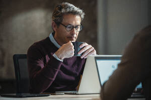 Architekt Vater trinkt Kaffee und schaut auf Laptop mit Sohn im Büro - JSRF02522