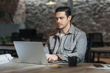 Architekt mit Laptop auf dem Tisch im Büro sitzend - JSRF02531