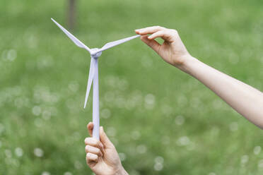 Geschäftsfrau hält Modell einer Windkraftanlage in der Natur - EKGF00240