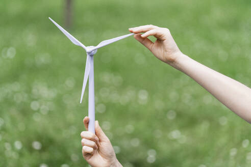 Geschäftsfrau hält Modell einer Windkraftanlage in der Natur - EKGF00240