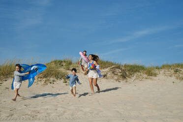 Happy family running at beach on sunny day - ASGF03860
