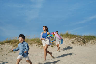 Glückliche Familie beim gemeinsamen Laufen am Strand - ASGF03861