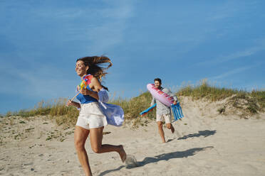 Glückliche Frau mit Mann läuft am Strand an einem sonnigen Tag - ASGF03862