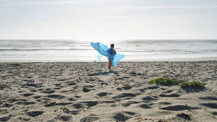Junge läuft mit aufblasbarem Spielzeug-Hai an einem sonnigen Tag am Strand - ASGF03865
