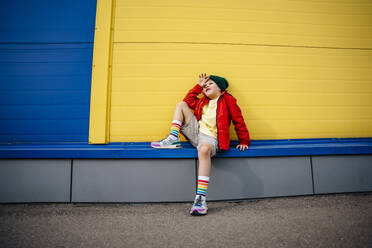 Nachdenklicher Junge sitzt vor einer gelben Wand - MDOF01354