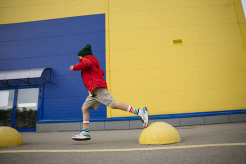 Boy running on bollards at street by building - MDOF01356