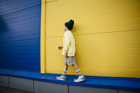 Boy wearing sweatshirt walking on wall by building - MDOF01362