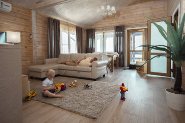 Sohn spielt mit Spielzeug auf dem Teppich im heimischen Wohnzimmer - ADF00116