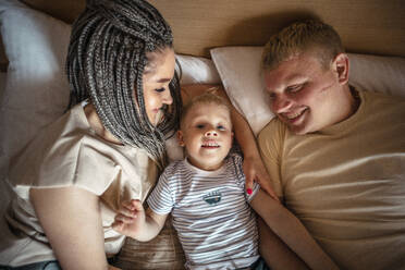 Eltern und Sohn liegen zu Hause auf dem Bett - ADF00121